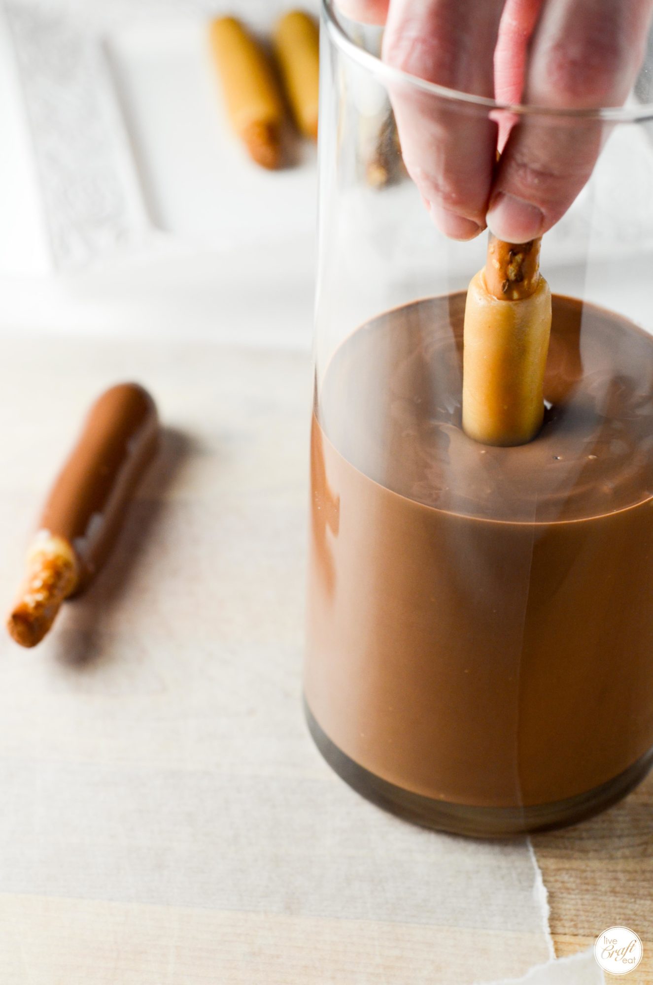 making chocolate-covered caramel pretzel rods